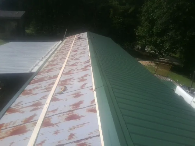 Old rusted panels beside newly installed green metal roofing — Wind Damage Roof Repair by Roofing Brothers in Marlborough