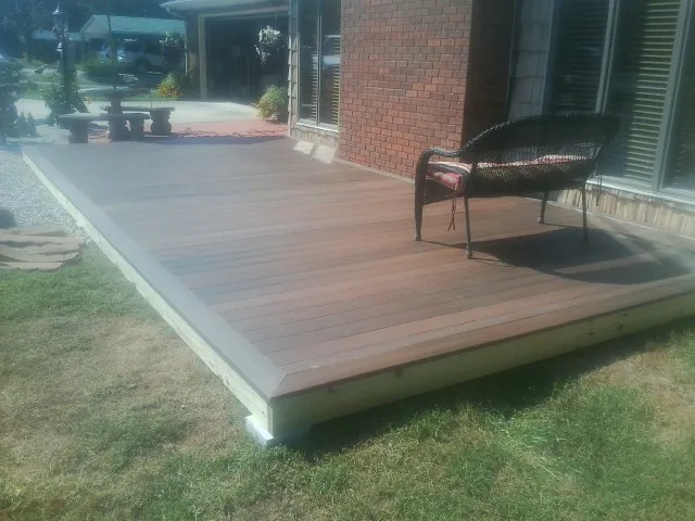 New wood deck and wicker chair beside a brick house in Marlborough