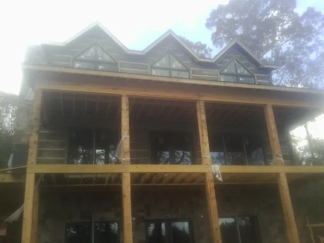 Dormers and porch framing on a large log home under construction — Roof Coating work by our crew in Marlborough